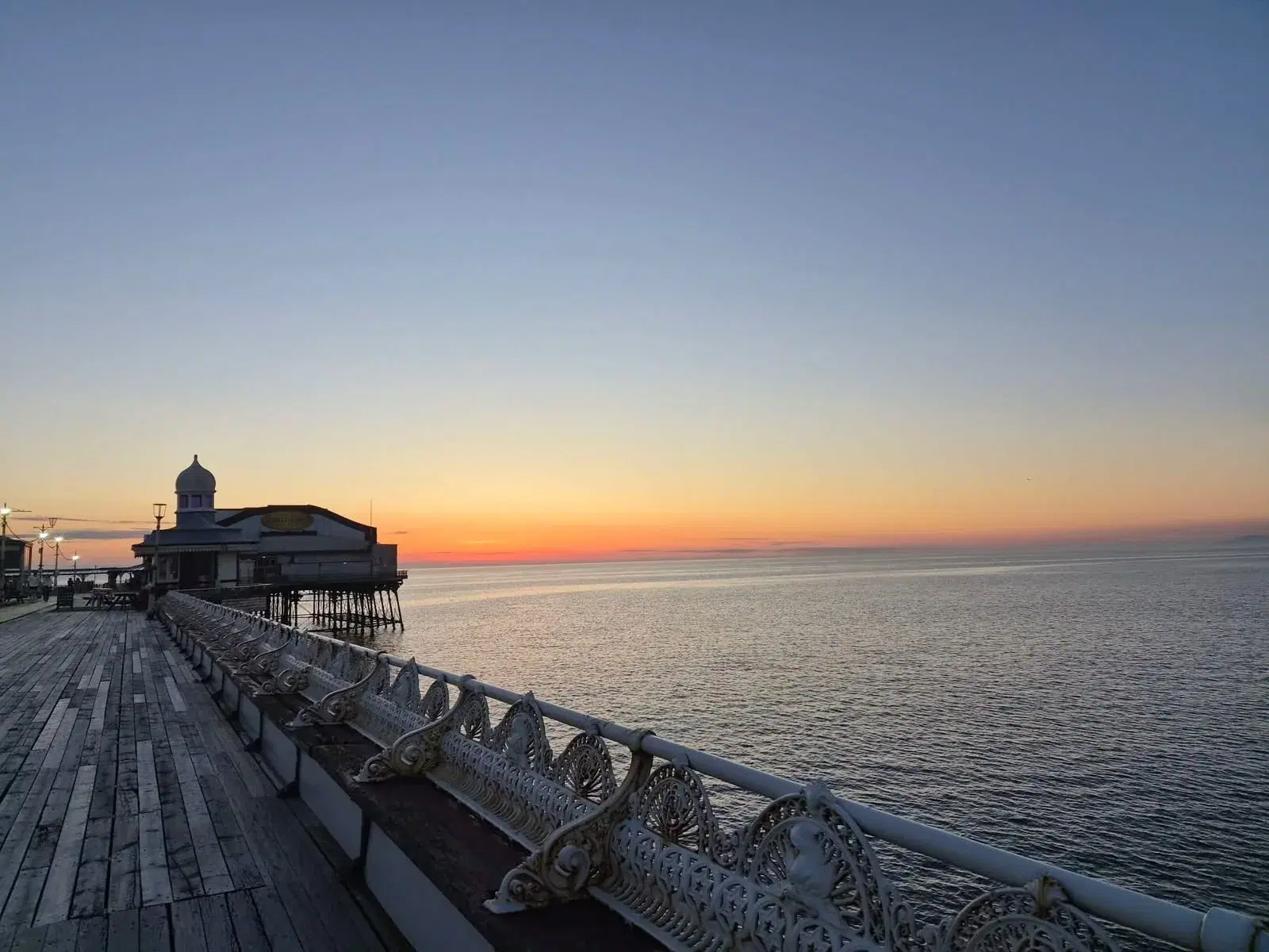 The North Pier boardwalk and ornate benches at sunset