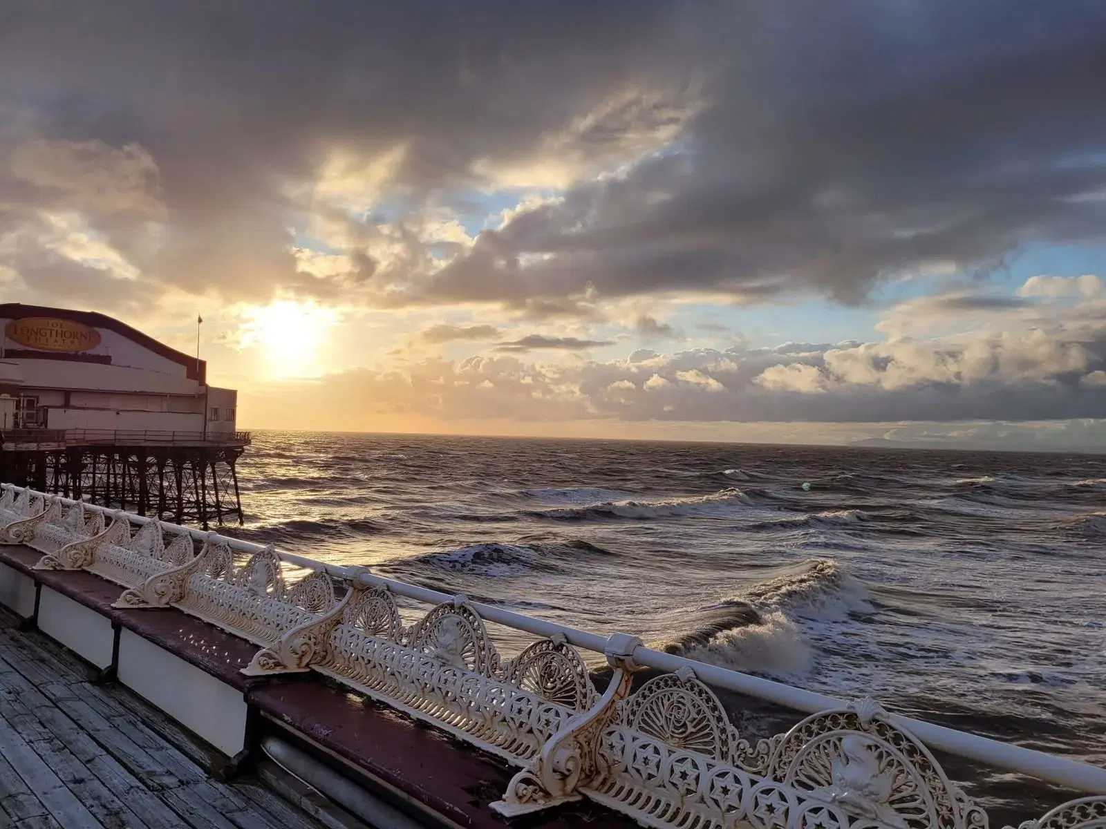 Waves and evening light seen beyond North Pier's ornate benches