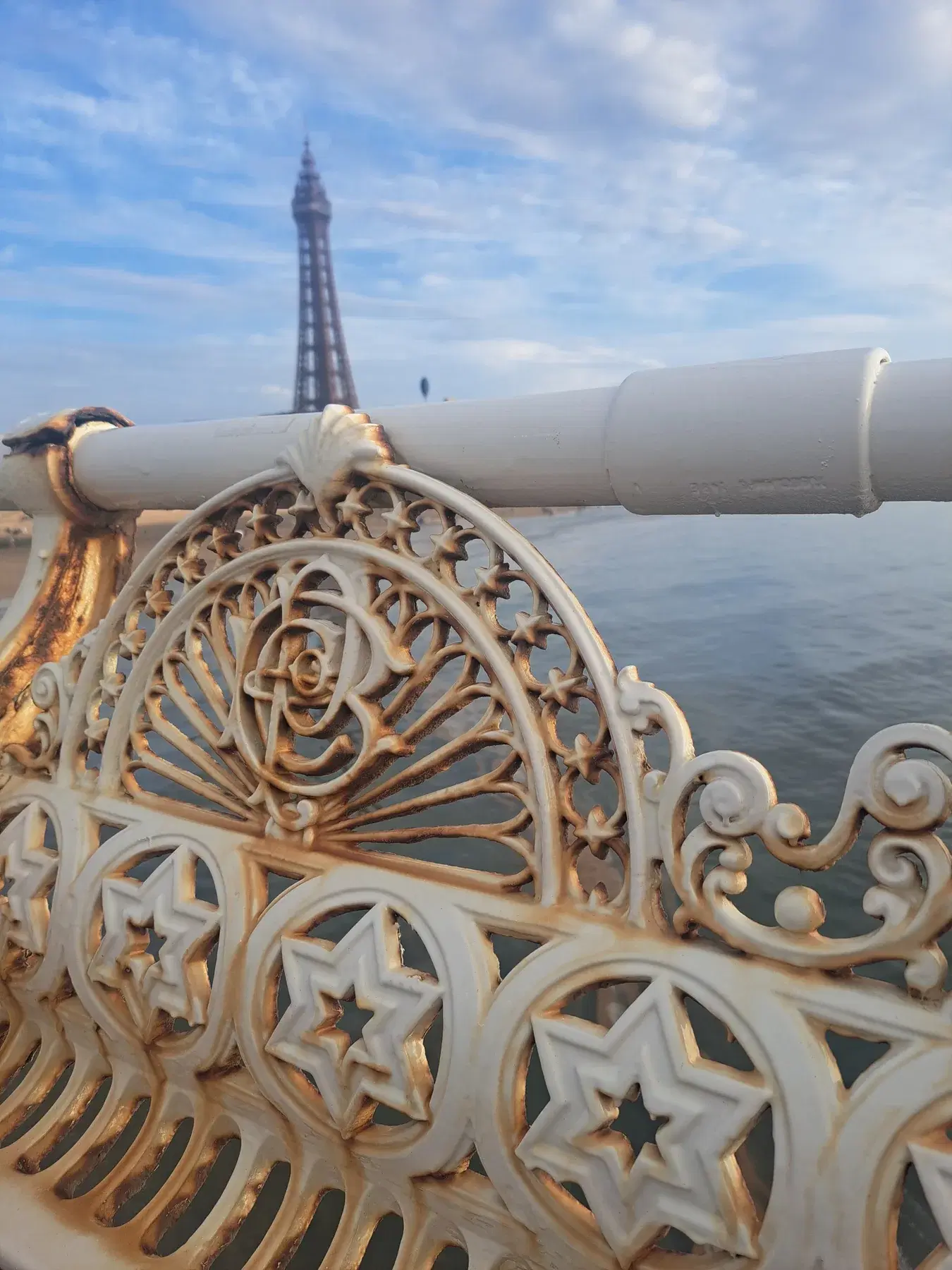 Ornate Victorian ironwork with a rose motif and five-pointed stars, with Blackpool Tower beyond